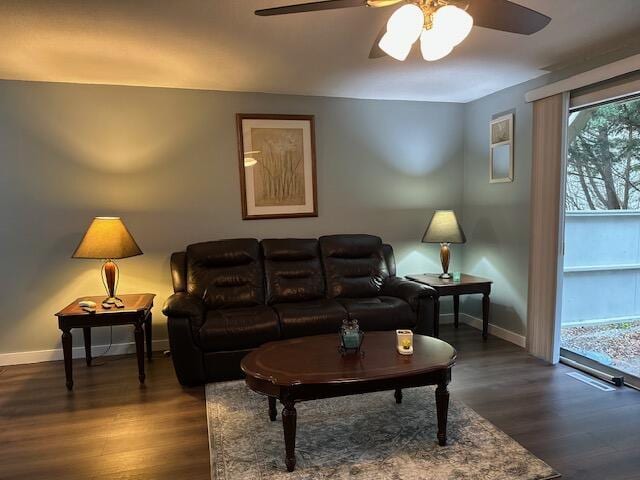 living room featuring baseboards, ceiling fan, and dark wood-style flooring