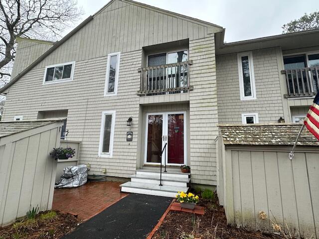 back of property with entry steps and a balcony
