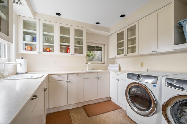 clothes washing area featuring sink, washer and clothes dryer, and cabinets