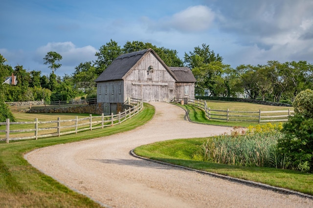 view of home's community featuring an outdoor structure, a lawn, and a rural view