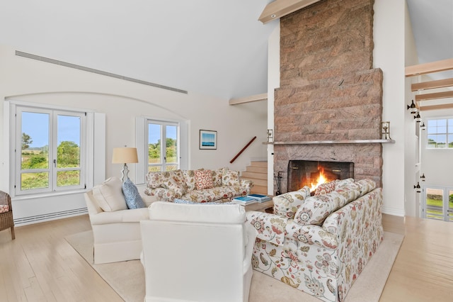 living room with baseboard heating, vaulted ceiling with beams, light hardwood / wood-style flooring, and a fireplace