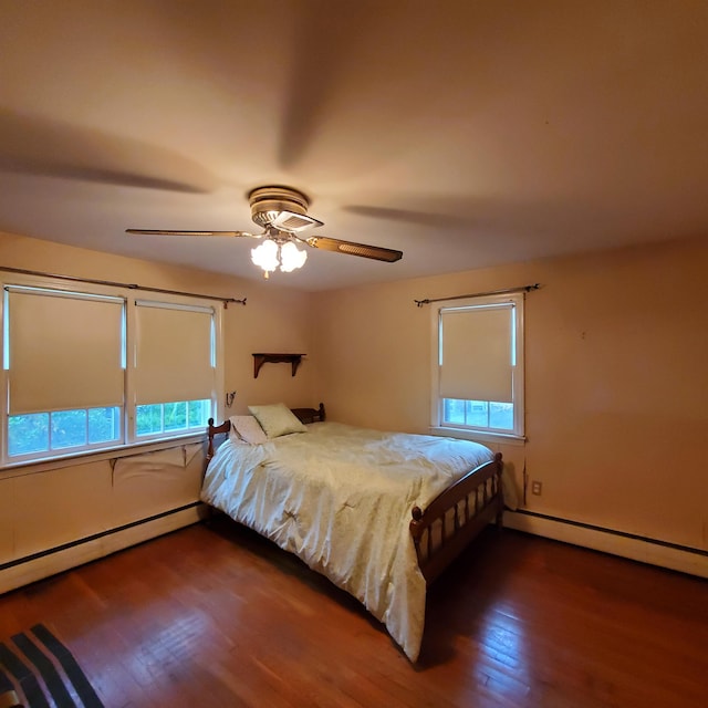 bedroom featuring baseboard heating, multiple windows, dark hardwood / wood-style floors, and ceiling fan