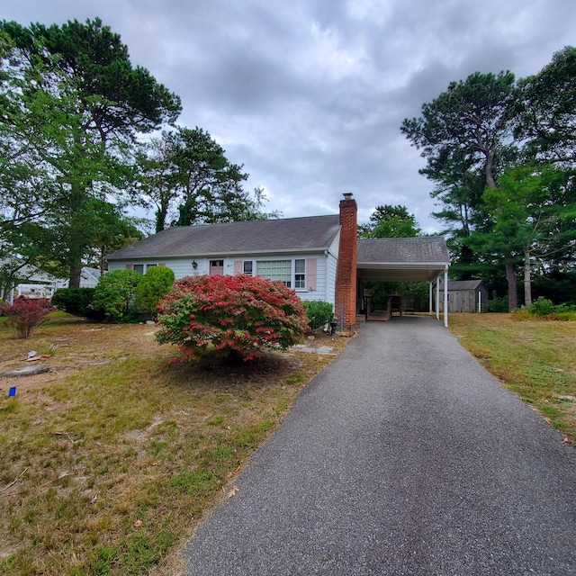 view of front of home featuring a front yard, a shed, and a carport