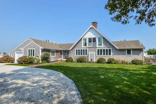 view of front of property featuring a balcony, a garage, and a front lawn