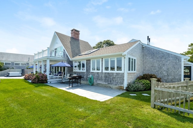 back of house featuring a balcony, a patio area, a lawn, and a jacuzzi