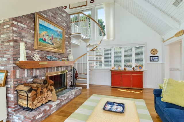 living room with hardwood / wood-style flooring, a brick fireplace, and lofted ceiling with beams