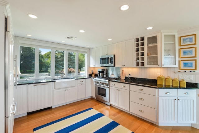 kitchen with sink, white cabinetry, light wood-type flooring, and high end appliances