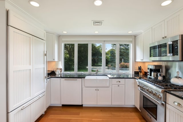 kitchen with sink, white cabinetry, appliances with stainless steel finishes, and dark stone countertops