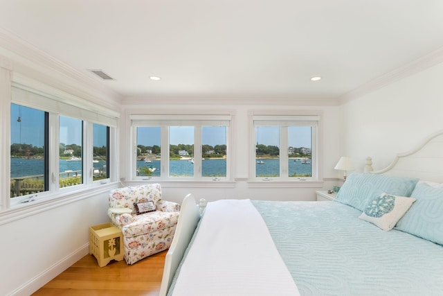 bedroom featuring a water view, ornamental molding, and multiple windows