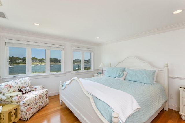 bedroom featuring light hardwood / wood-style floors, a water view, and ornamental molding