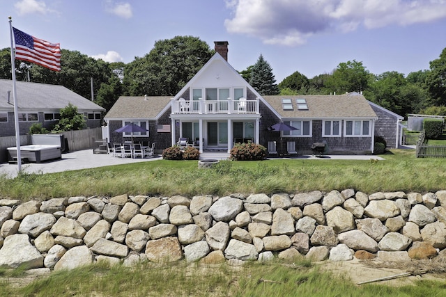 back of house with a balcony, a patio area, and a hot tub