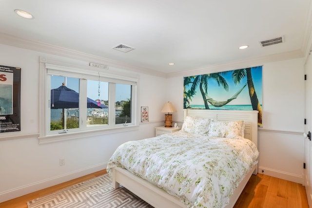 bedroom featuring crown molding and light hardwood / wood-style floors