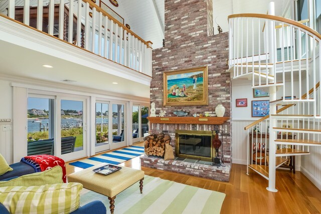 living room with a towering ceiling, a brick fireplace, and light hardwood / wood-style floors