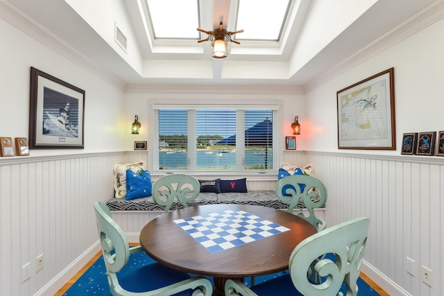 dining space featuring ornamental molding, a skylight, and a raised ceiling