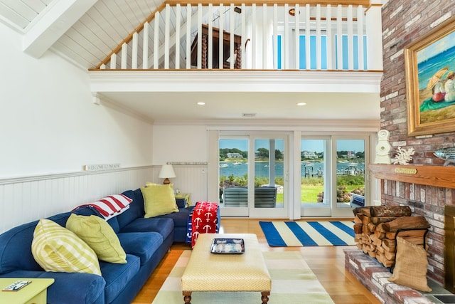 living room featuring light hardwood / wood-style floors, beam ceiling, and a brick fireplace