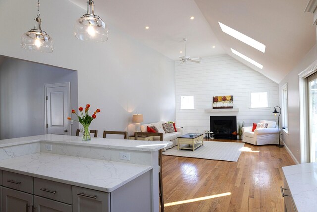 55 Blue Castle Dr, Mashpee, MA 02649 - kitchen featuring light wood-style floors, a skylight, a fireplace, open floor plan, and pendant lighting