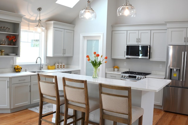 55 Blue Castle Dr, Mashpee, MA 02649 - kitchen with appliances with stainless steel finishes, a sink, vaulted ceiling, light wood-type flooring, and a breakfast bar