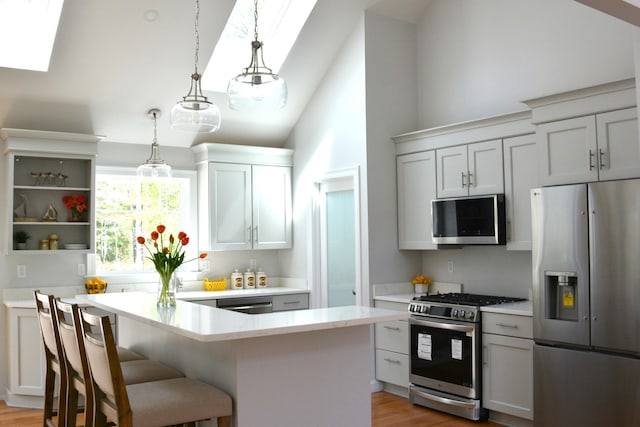 55 Blue Castle Dr, Mashpee, MA 02649 - kitchen with stainless steel appliances, a skylight, high vaulted ceiling, pendant lighting, and a breakfast bar
