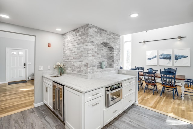 46 Juniper Ln W, South Chatham, MA 02659 - kitchen featuring light stone countertops, a sink, light wood-style floors, stainless steel oven, and wine cooler