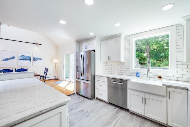 46 Juniper Ln W, South Chatham, MA 02659 - kitchen with decorative backsplash, a sink, white cabinets, lofted ceiling, and stainless steel appliances