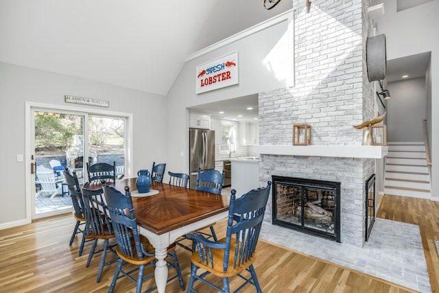 46 Juniper Ln W, South Chatham, MA 02659 - dining area with a fireplace, light wood-style floors, high vaulted ceiling, stairs, and baseboards