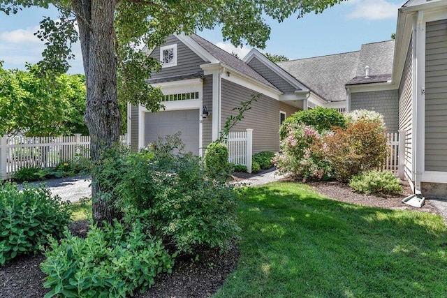 view of side of home with a garage, a yard, and fence