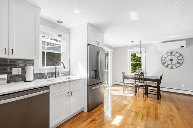 29 Braeburn Ct, Hatchville, MA 02536 - kitchen with appliances with stainless steel finishes, a wall mounted air conditioner, a sink, white cabinets, and pendant lighting