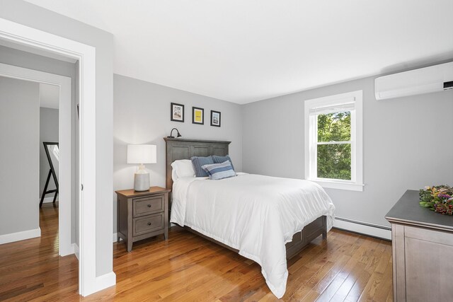 29 Braeburn Ct, Hatchville, MA 02536 - bedroom with a baseboard heating unit, an AC wall unit, wood finished floors, and baseboards