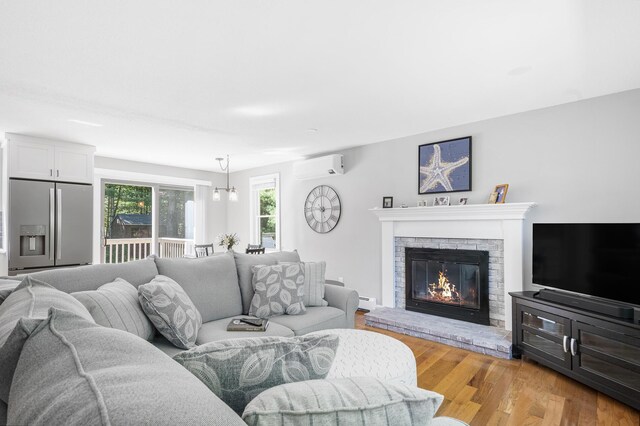 29 Braeburn Ct, Hatchville, MA 02536 - living area featuring a wall mounted air conditioner, light wood finished floors, a brick fireplace, and baseboard heating