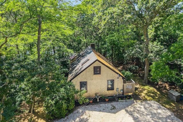 50 Piper Ln, Eastham, MA 02642 - view of home's exterior with a chimney and a wooded view
