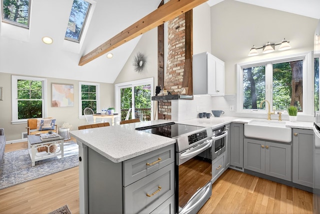 50 Piper Ln, Eastham, MA 02642 - kitchen with stainless steel range with electric cooktop, gray cabinets, high vaulted ceiling, light stone countertops, and a peninsula
