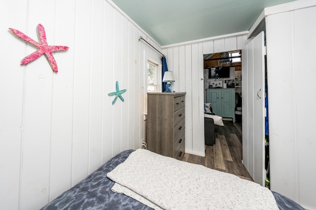 bedroom with wood walls and dark hardwood / wood-style flooring