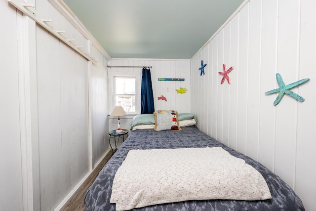 bedroom with wooden walls and dark wood-type flooring