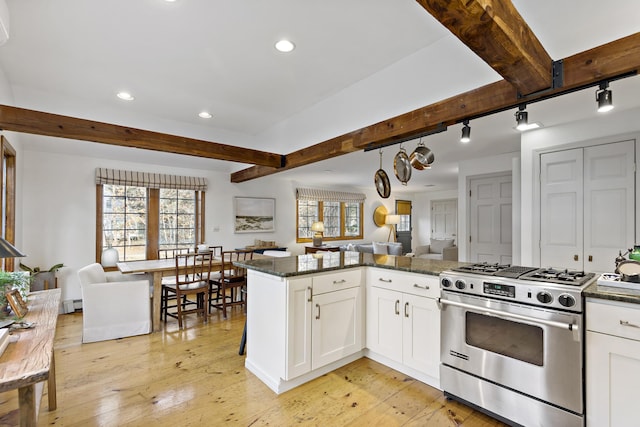 kitchen with open floor plan, beamed ceiling, stainless steel gas range, and a healthy amount of sunlight