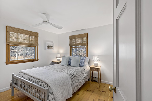 bedroom featuring a ceiling fan, baseboards, light wood-type flooring, and baseboard heating