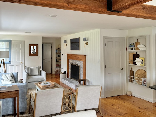 living area featuring a fireplace with raised hearth, light wood-style flooring, and visible vents