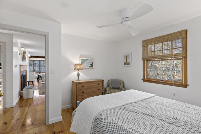 bedroom with light wood-type flooring, baseboards, and ceiling fan