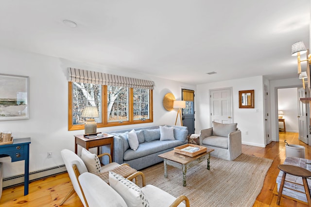 living room with visible vents, baseboards, baseboard heating, and light wood finished floors