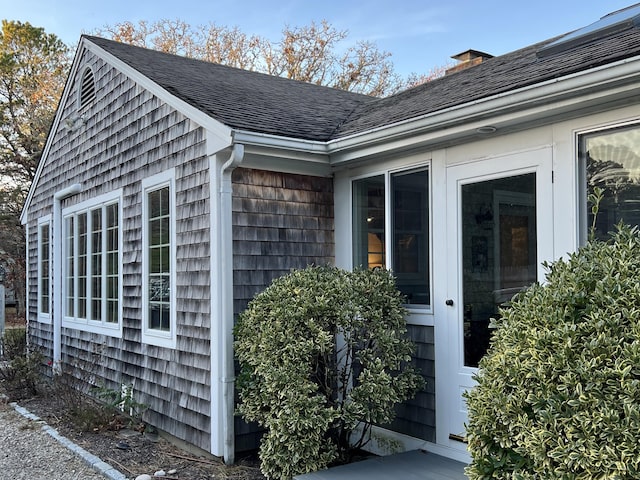 view of property exterior with a chimney and a shingled roof