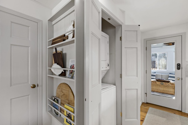 laundry room featuring stacked washer and dryer, light wood-style flooring, and laundry area