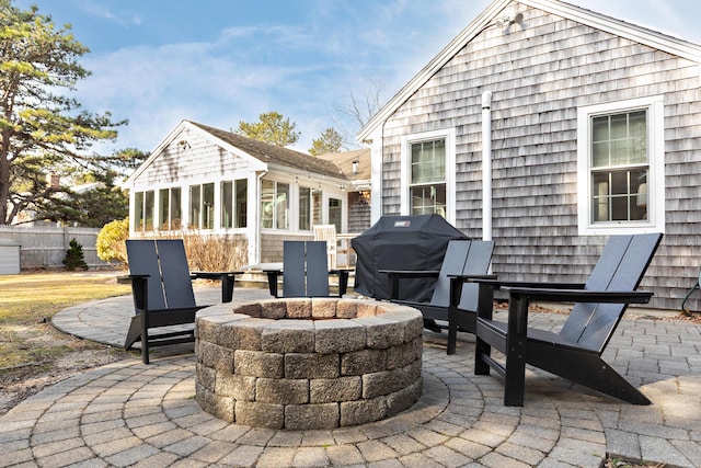 view of patio / terrace with area for grilling, an outdoor fire pit, a sunroom, and fence