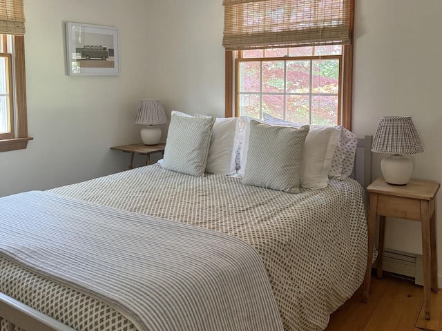 bedroom featuring a baseboard heating unit and wood finished floors