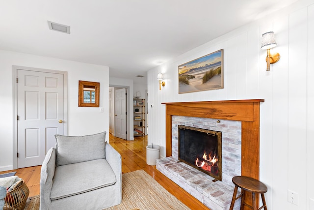 living room with a brick fireplace and hardwood / wood-style floors