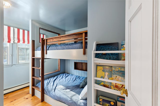 bedroom with a baseboard heating unit and wood finished floors