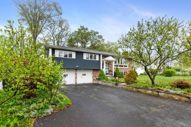 88 Hilltop St, Milton, MA 02186 - split foyer home featuring asphalt driveway, a garage, and brick siding