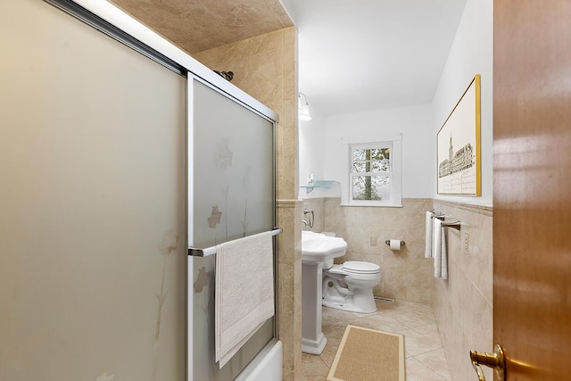 88 Hilltop St, Milton, MA 02186 - full bathroom with tile patterned floors, toilet, tile walls, wainscoting, and combined bath / shower with glass door