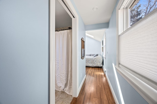 corridor with baseboards and wood finished floors