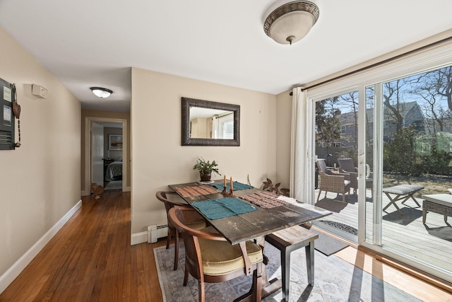 dining room with a baseboard heating unit, baseboards, and wood finished floors