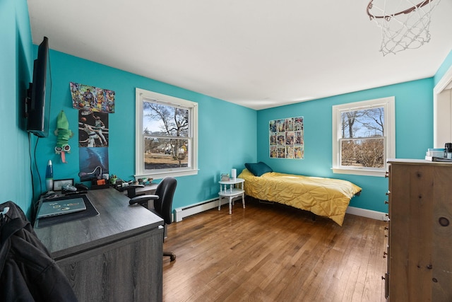 bedroom featuring a baseboard heating unit, wood-type flooring, and baseboards