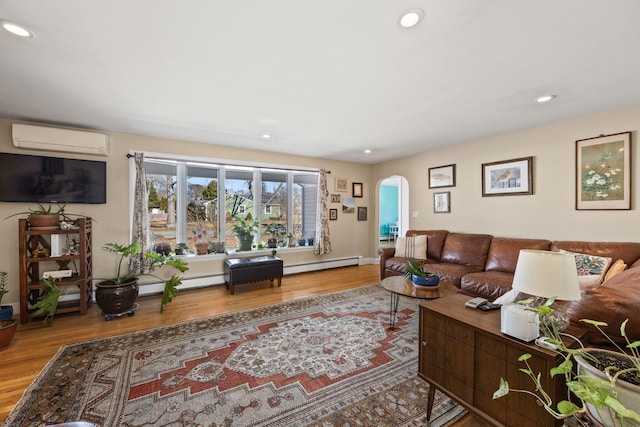 living room with arched walkways, recessed lighting, an AC wall unit, and wood finished floors